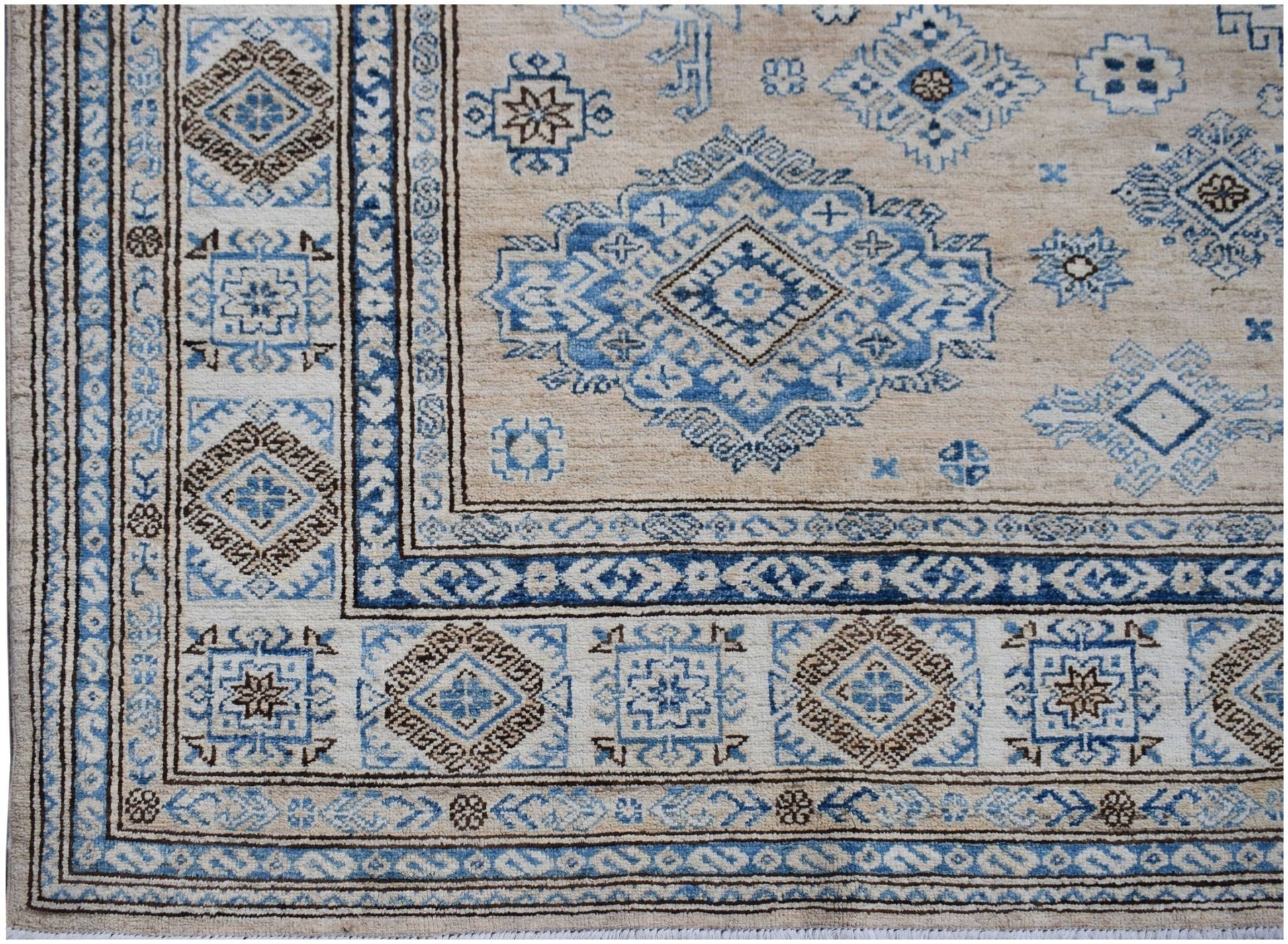 Handmade Afghan Super Kazakh rug featuring traditional blue and brown geometric motifs on beige.