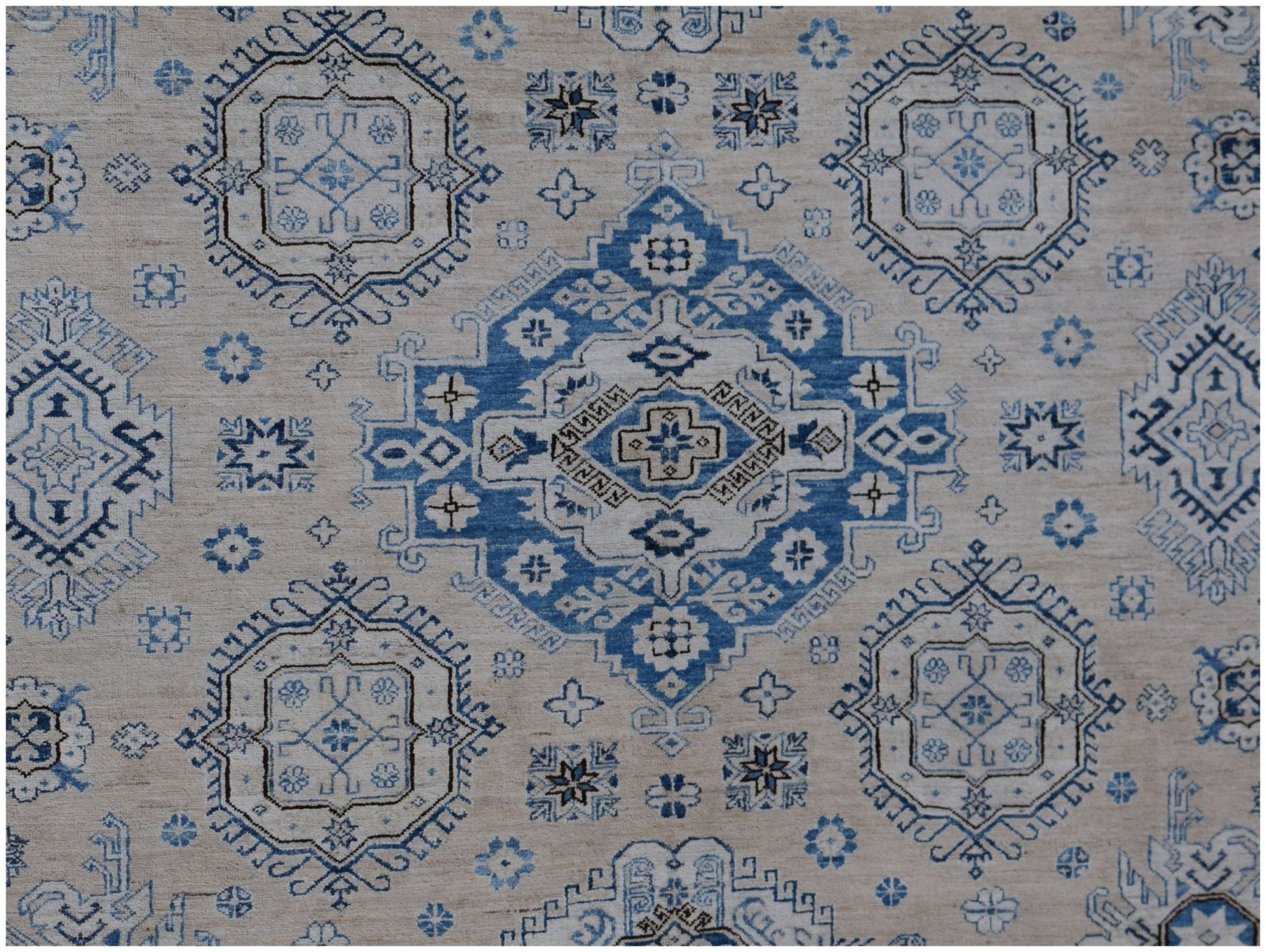 Handmade Afghan Super Kazakh rug featuring traditional blue geometric motifs on a beige background.