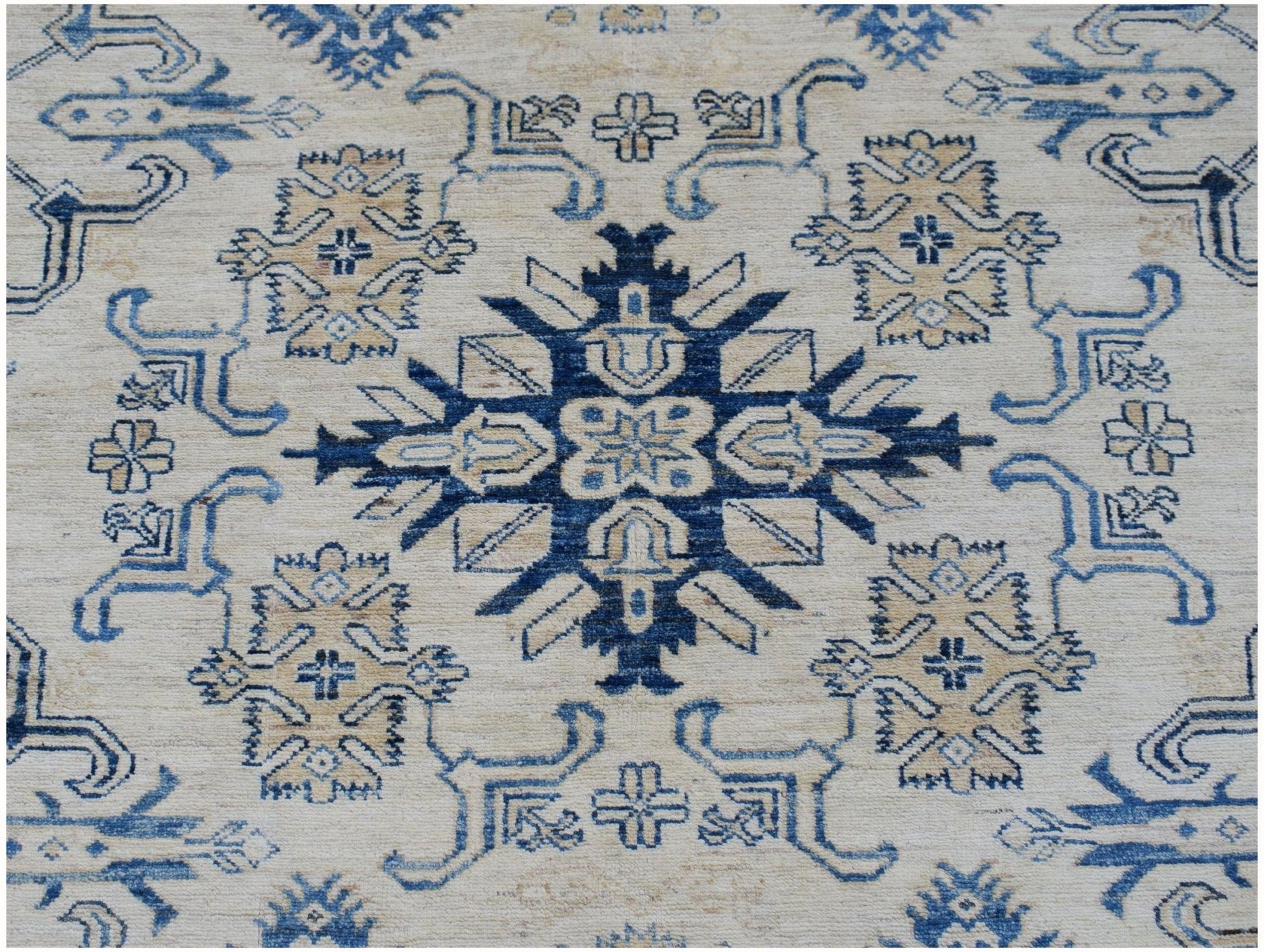Handmade Afghan Super Kazakh rug featuring a central blue geometric medallion on a cream field.
