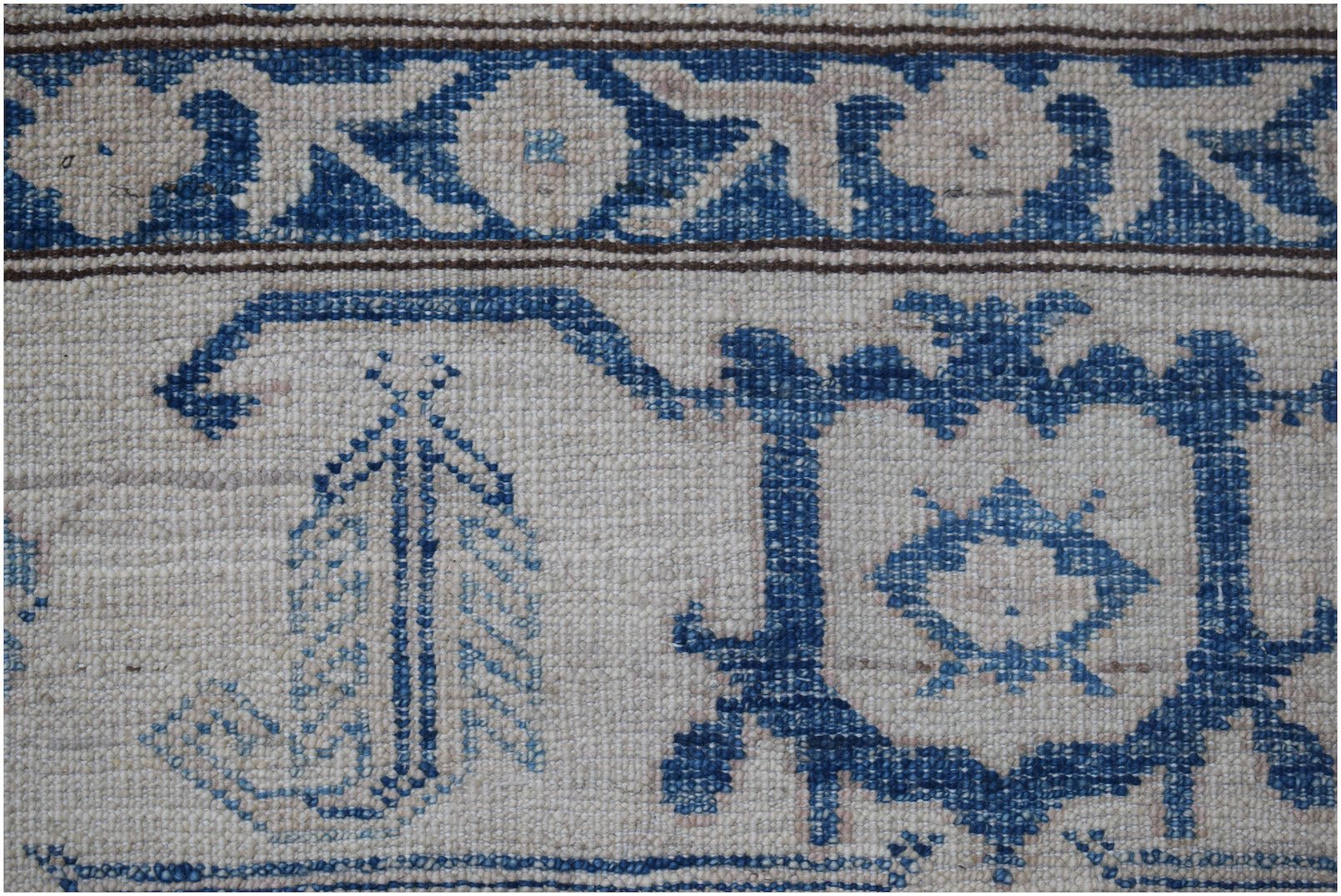 A close-up of an Afghan Super Kazakh rug featuring traditional blue geometric motifs on cream wool.