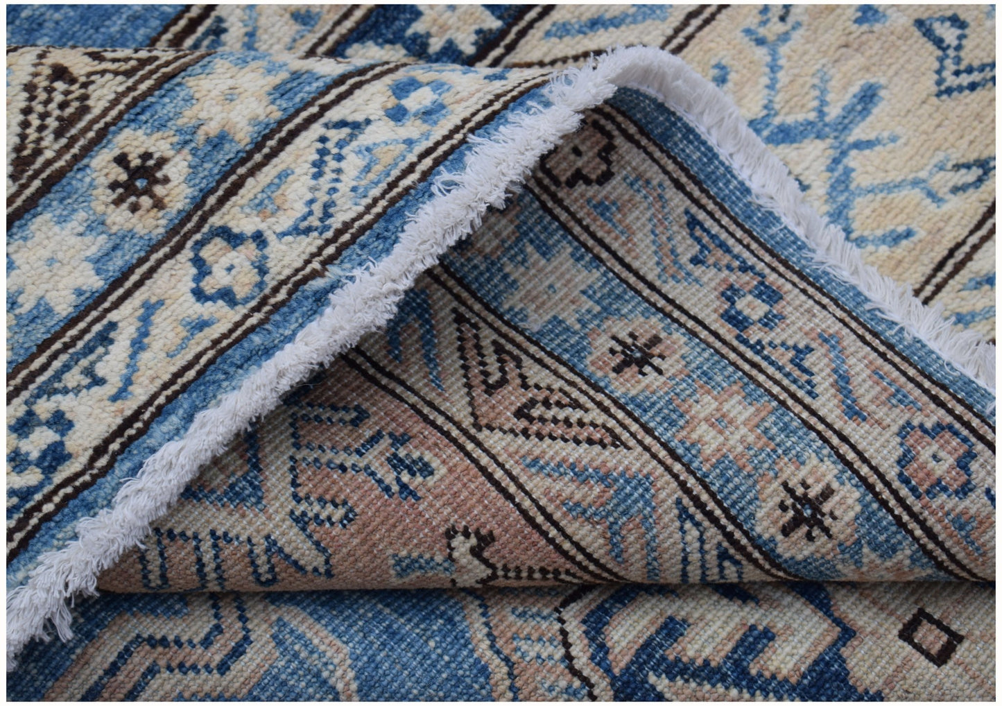 A handmade Afghan Super Kazakh wool rug featuring traditional blue and cream geometric patterns.