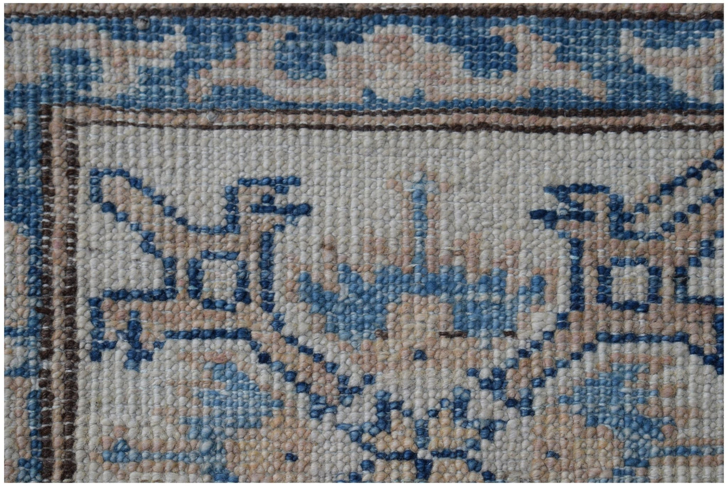 A close-up of an Afghan Super Kazakh rug featuring intricate blue and beige geometric patterns.