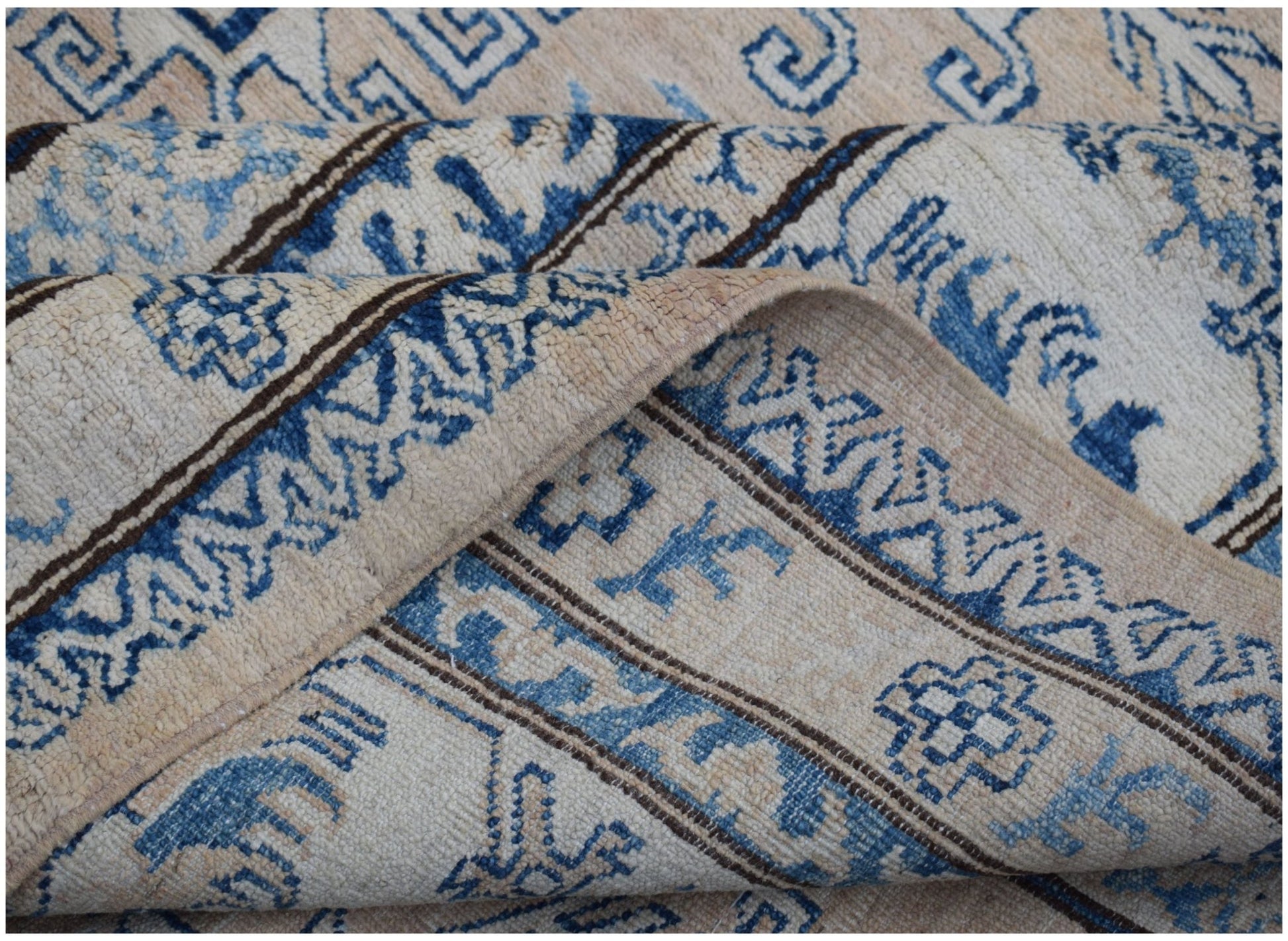 A handmade Afghan Super Kazakh rug featuring traditional blue geometric motifs on a cream background.