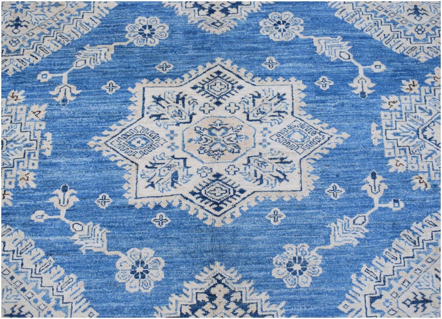 A handmade Afghan Super Kazakh rug featuring a central star medallion in blue and cream wool.