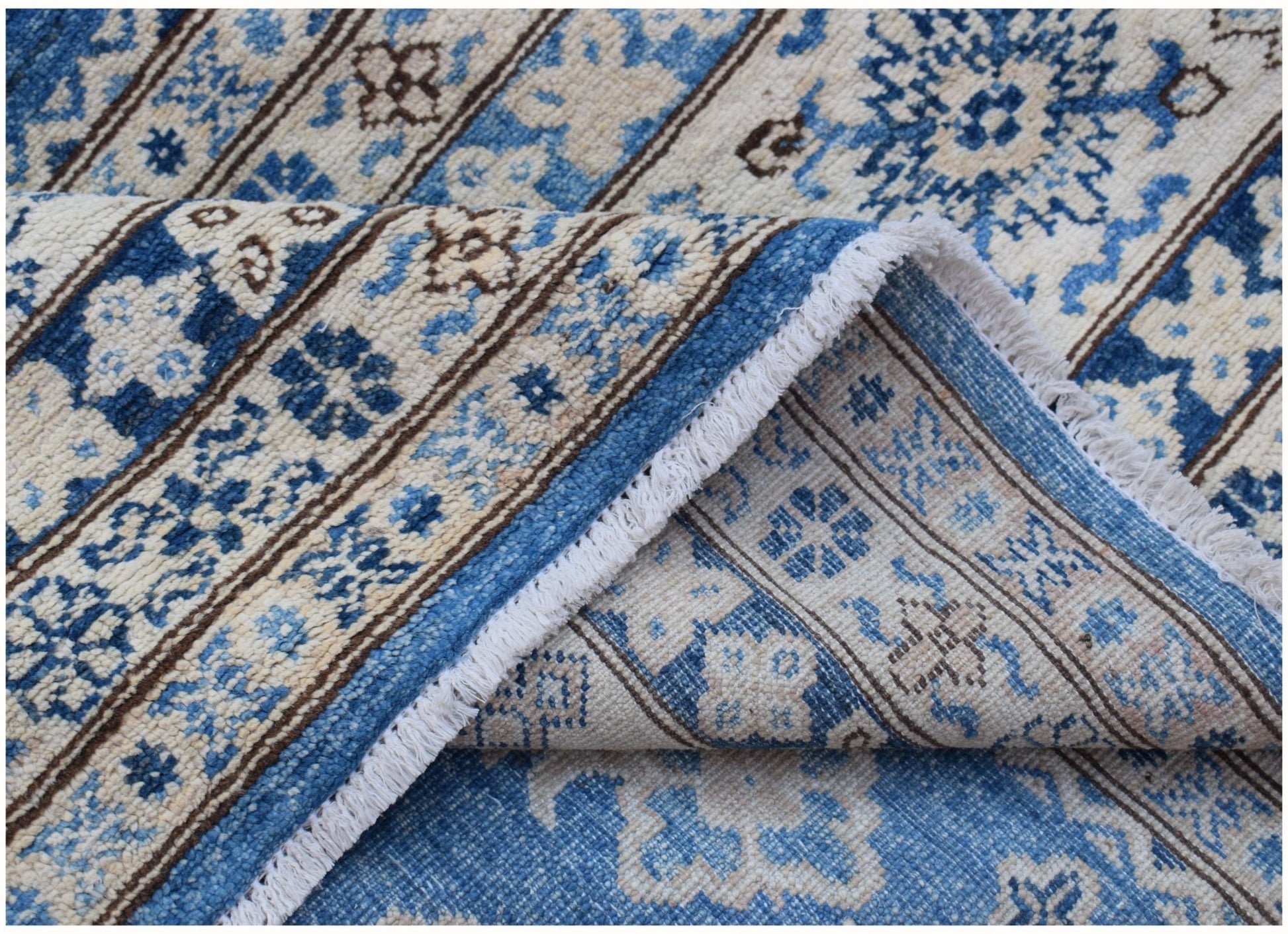 A handmade Afghan Super Kazakh rug featuring traditional blue and cream floral patterns.