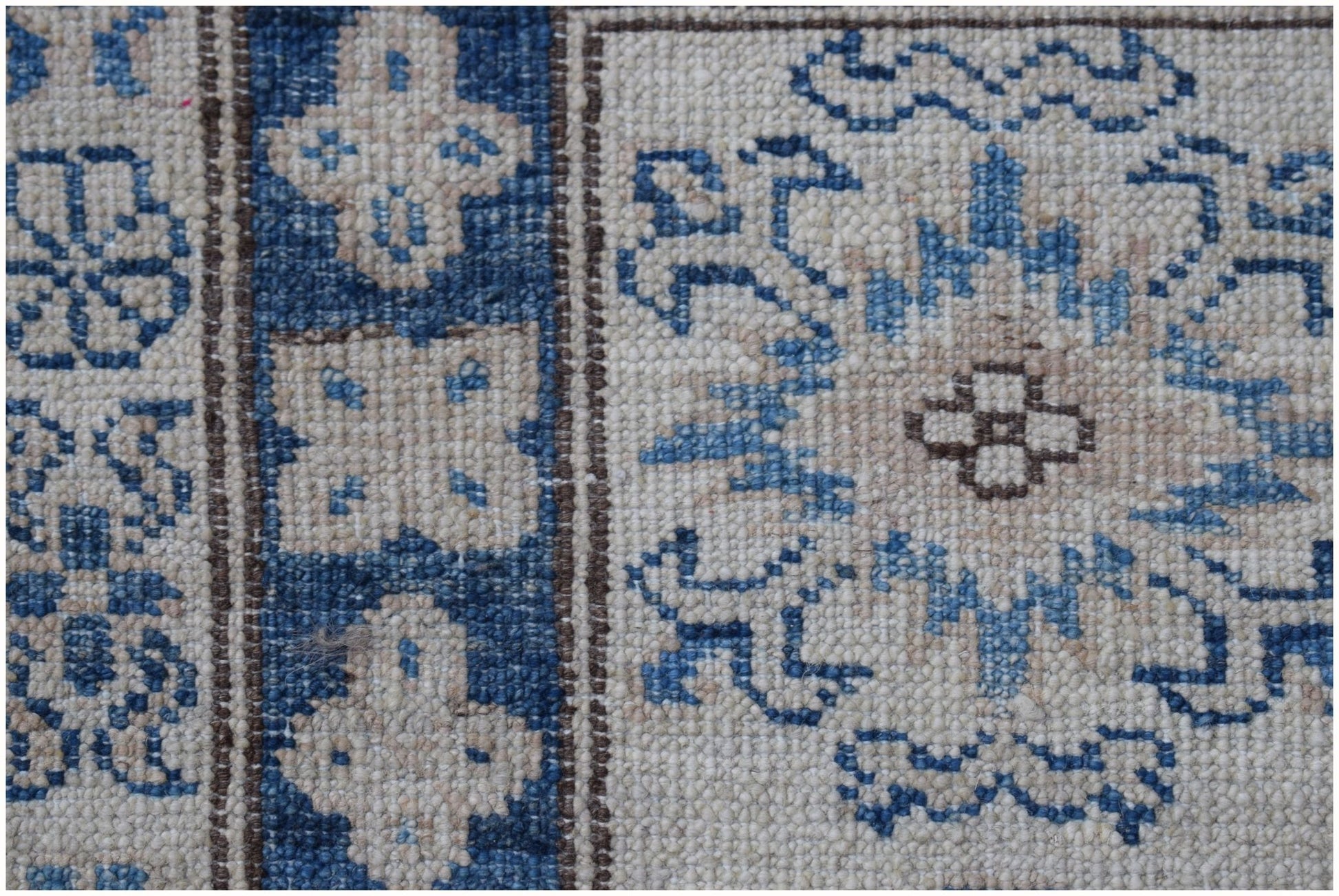 A close-up of an Afghan Super Kazakh rug featuring blue and cream geometric floral patterns.