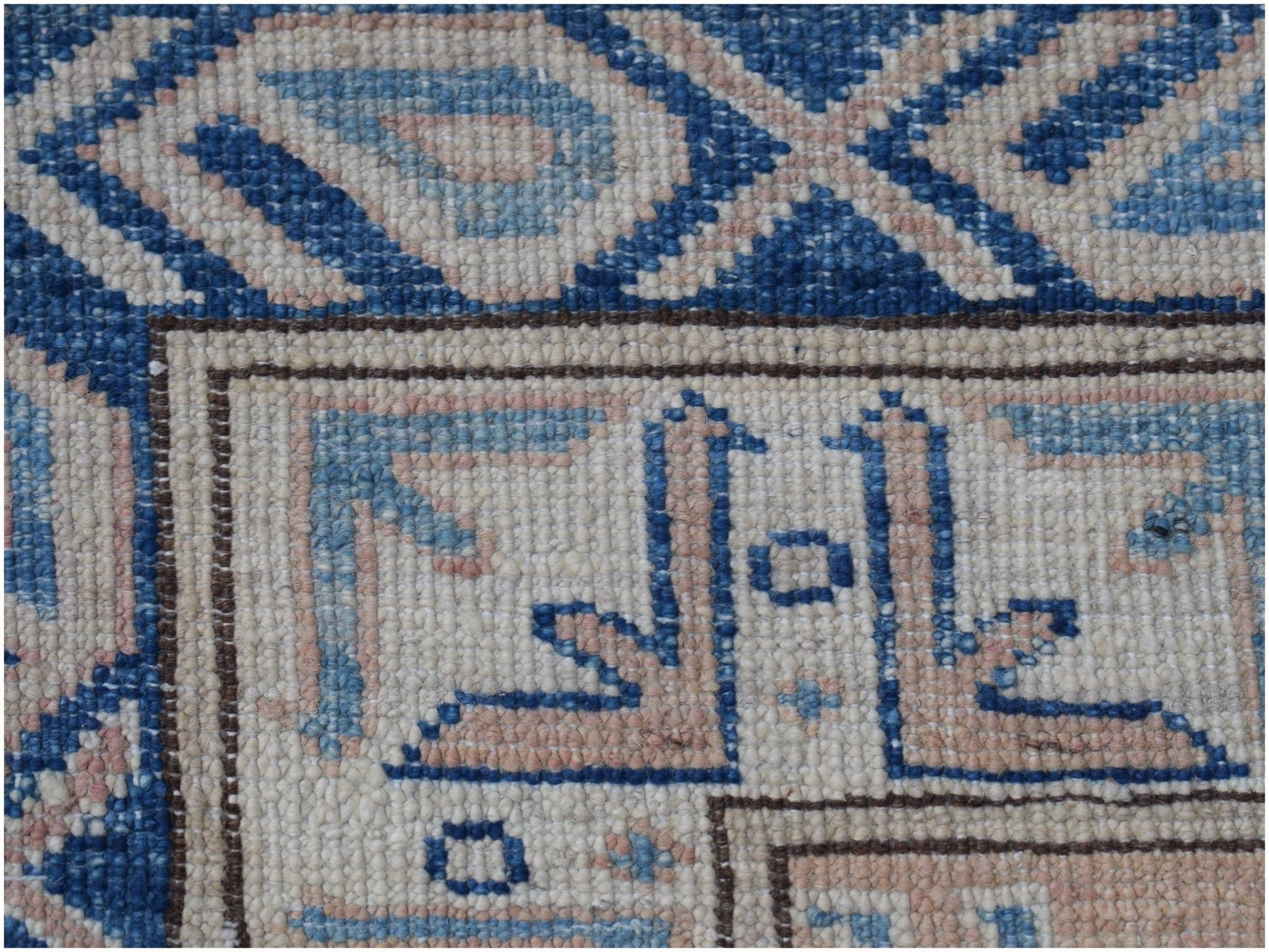 A close-up of an Afghan Super Kazakh rug featuring intricate blue and beige geometric patterns.