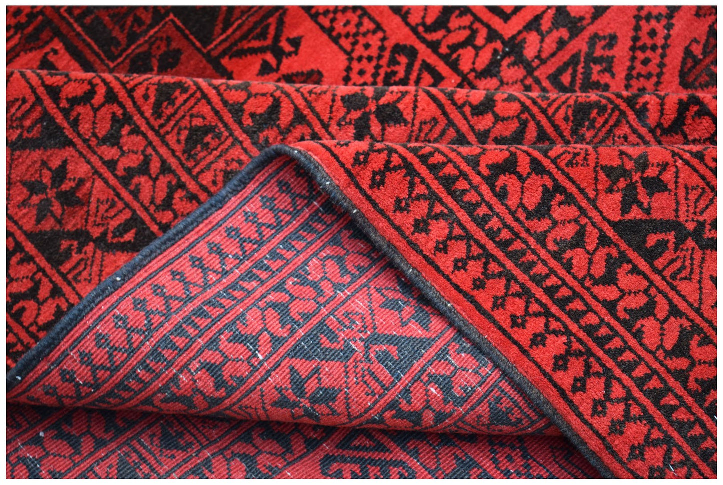 A vintage handmade Afghan Turkmen rug featuring a repeating geometric pattern in red and black.