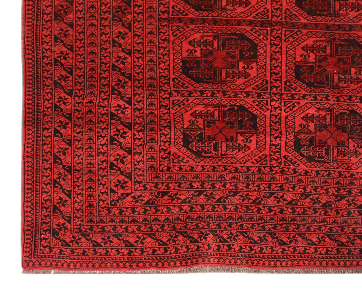 A vintage Afghan Turkmen rug featuring traditional geometric octagonal motifs in red and black.