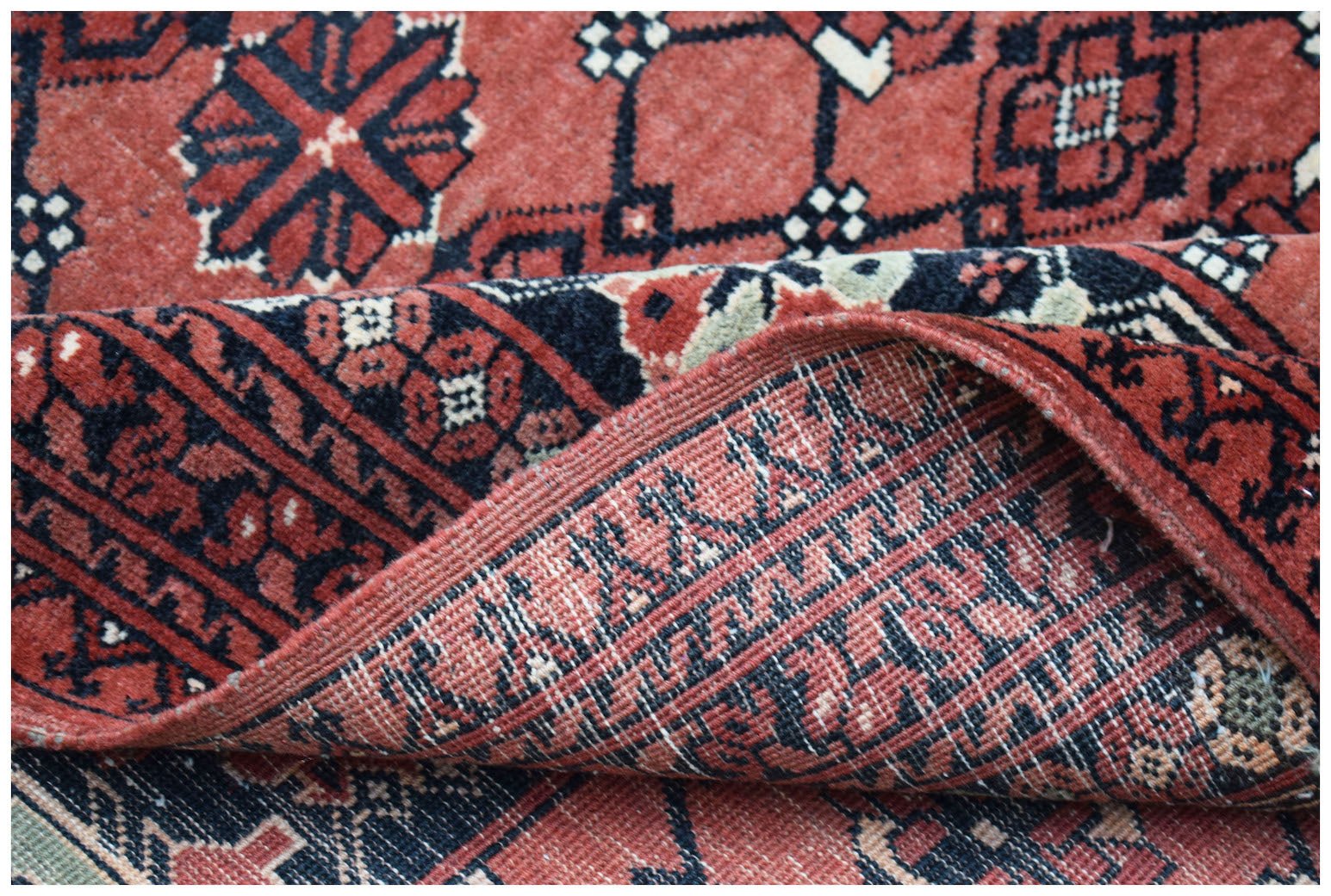 A vintage Afghan Turkmen rug featuring a geometric elephant foot motif in red and black wool.