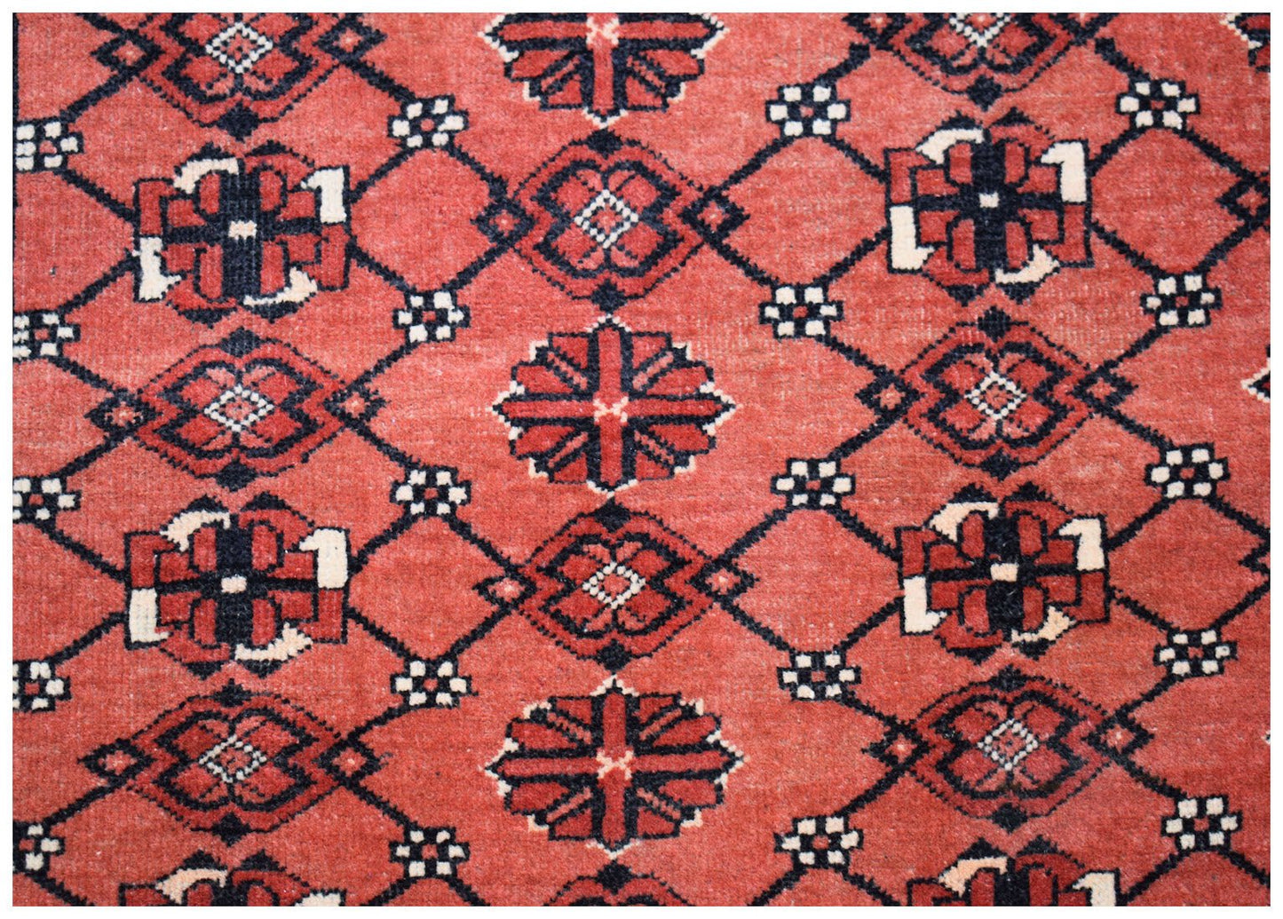 A vintage Afghan Turkmen rug featuring a repeating geometric Elephant's Foot motif in red and black.
