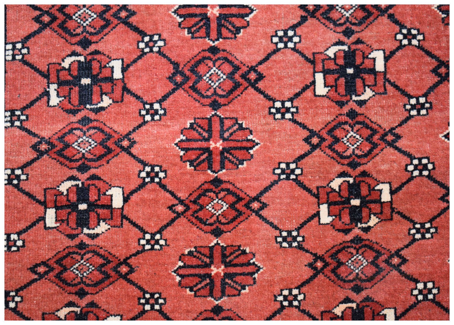A vintage Afghan Turkmen rug featuring a repeating geometric Elephant's Foot motif in red and black.