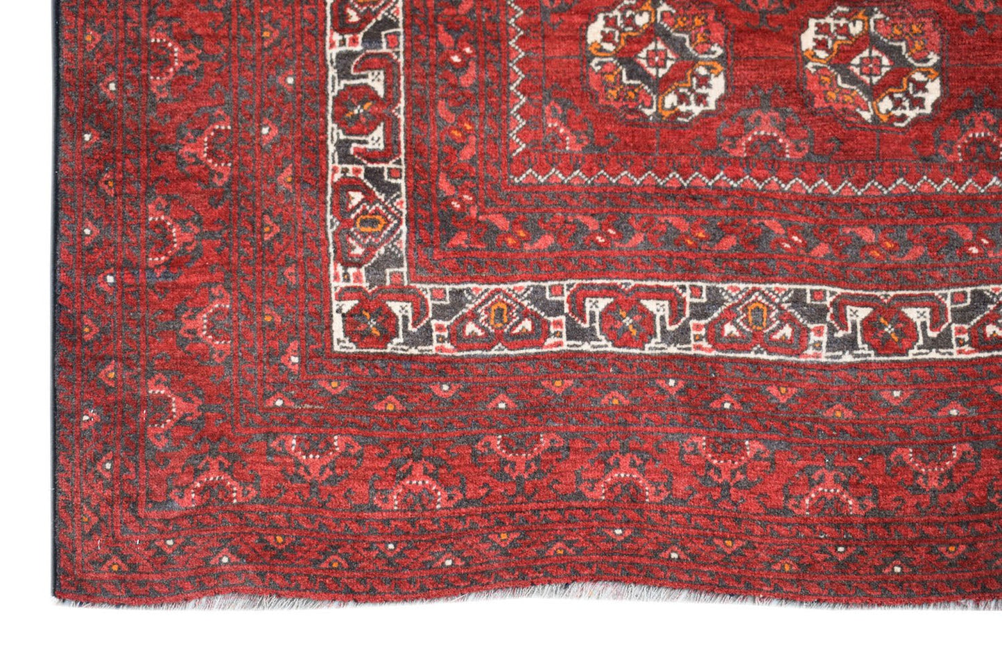 A vintage Afghan Turkmen rug featuring traditional geometric patterns in deep red and charcoal.