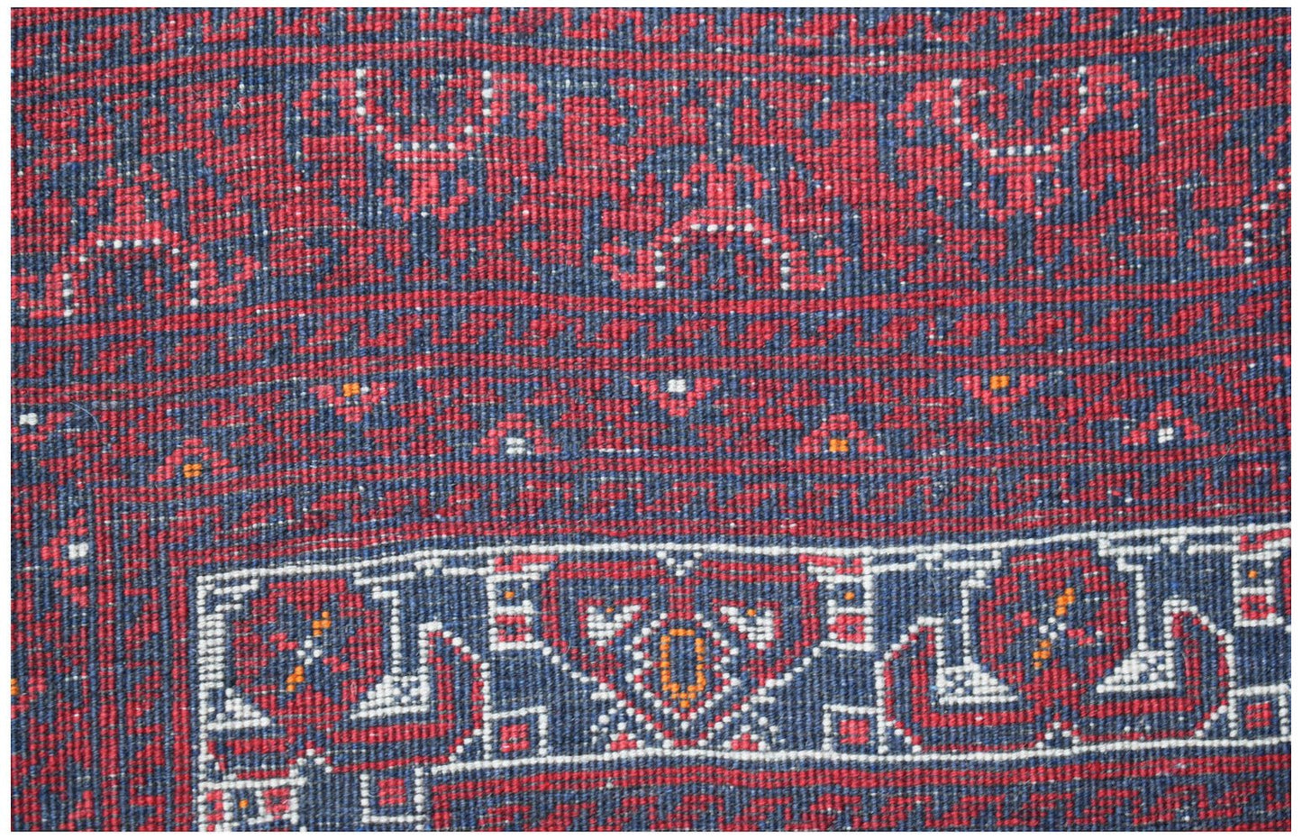 A vintage handmade Afghan Turkmen wool rug featuring traditional red and blue geometric patterns.