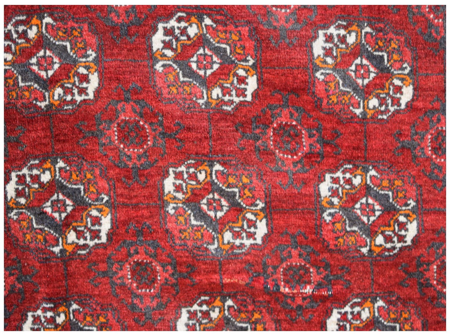A vintage Afghan Turkmen rug featuring a repeating geometric pattern in red, black, and white.