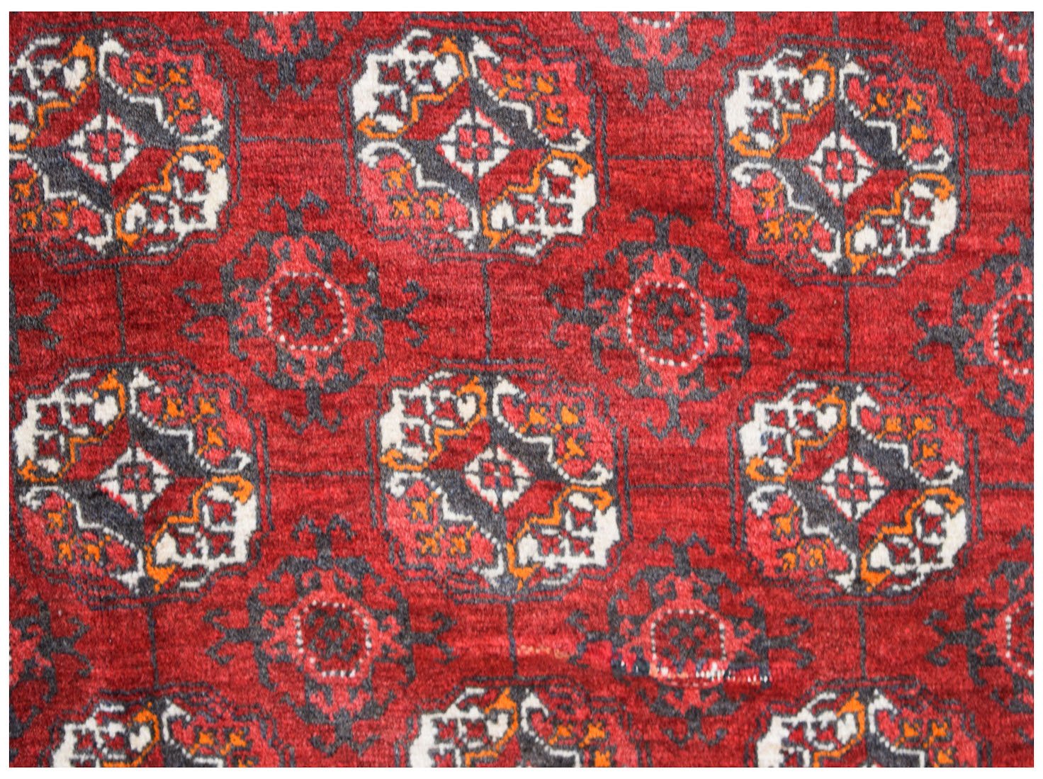 A vintage Afghan Turkmen rug featuring a repeating geometric pattern in red, black, and white.