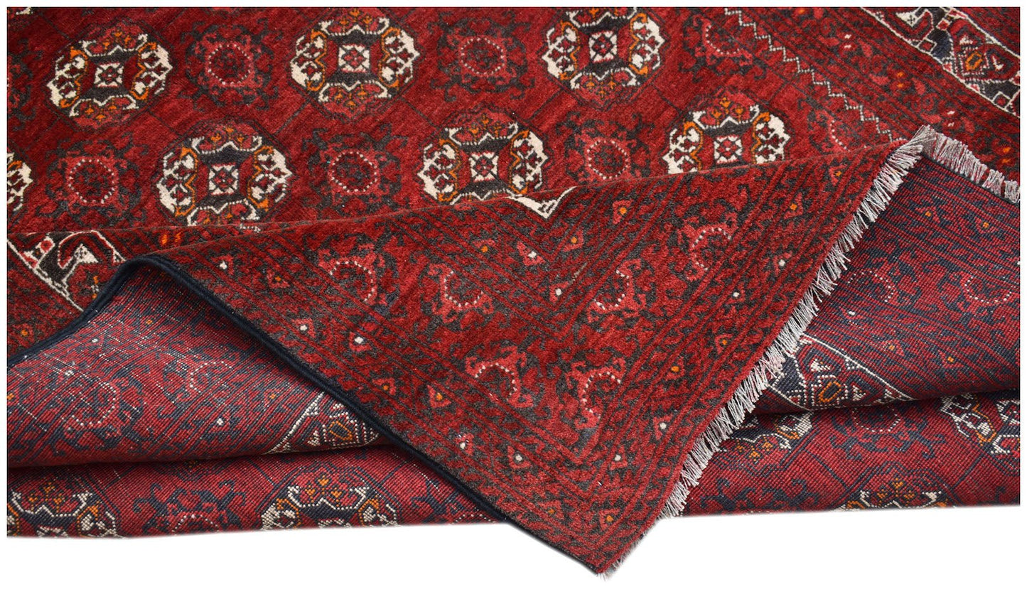 Vintage Afghan Turkmen rug with a red background and geometric patterns.