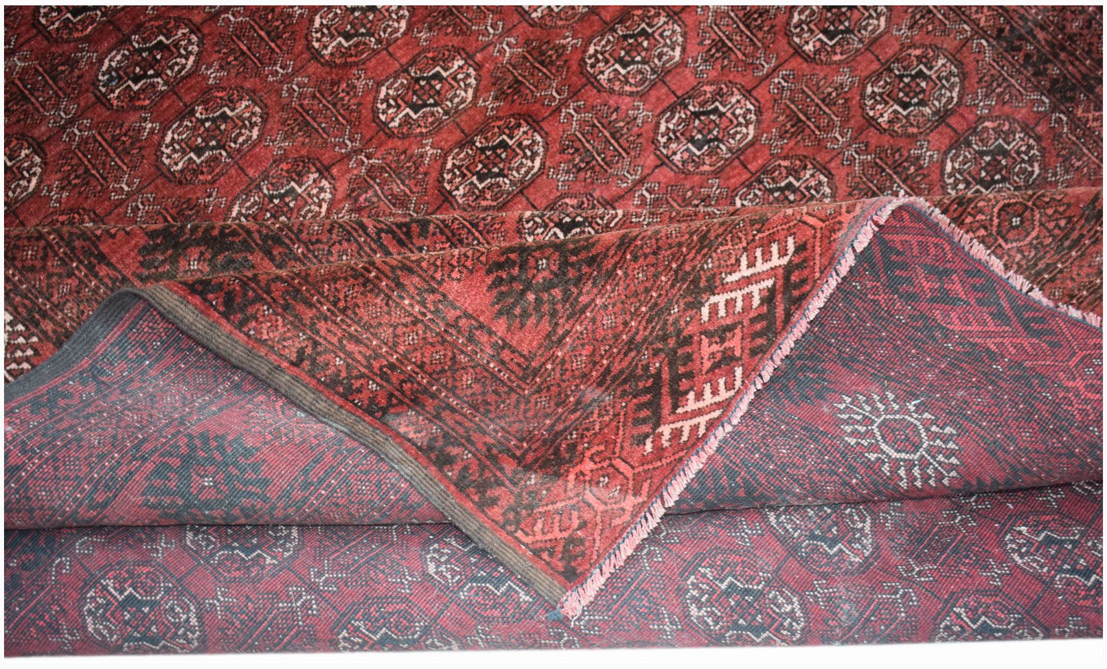 A vintage Afghan Turkmen wool rug featuring a red geometric elephant foot motif.