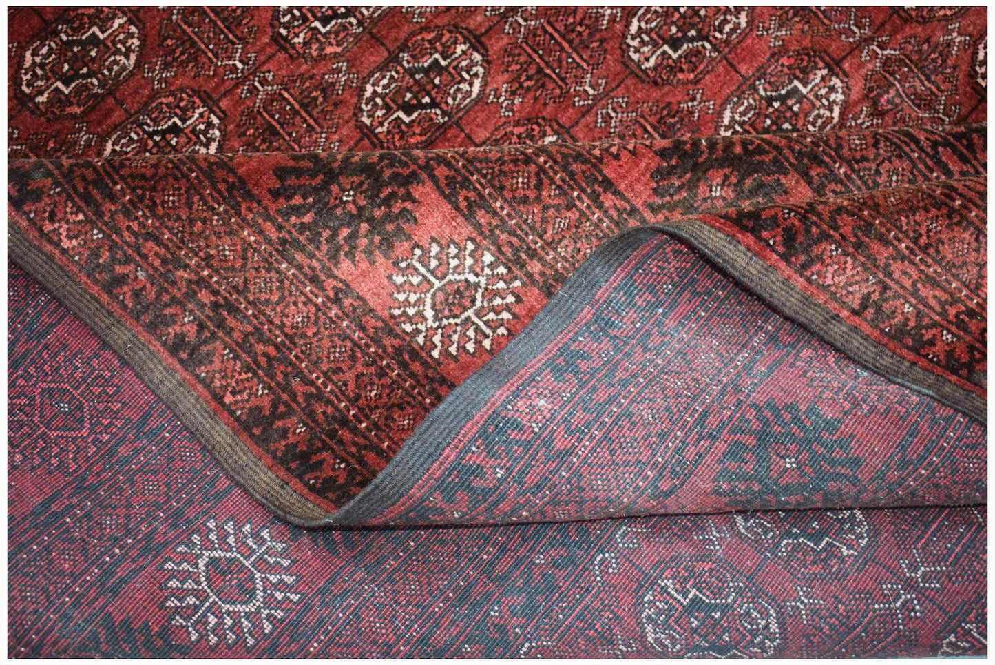 A vintage handmade Afghan Turkmen wool rug featuring a traditional red and black geometric pattern.
