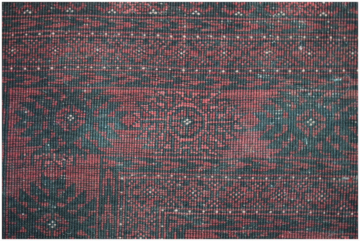 A vintage handmade Afghan Turkmen wool rug featuring a traditional red and black geometric pattern.