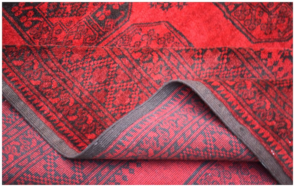 A vintage handmade Afghan Turkmen wool rug featuring a traditional red and black geometric pattern.