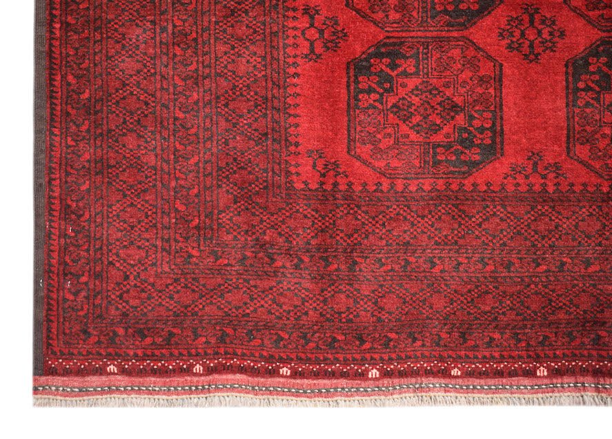 A vintage handmade Afghan Turkmen rug featuring traditional octagonal motifs in red and black wool.