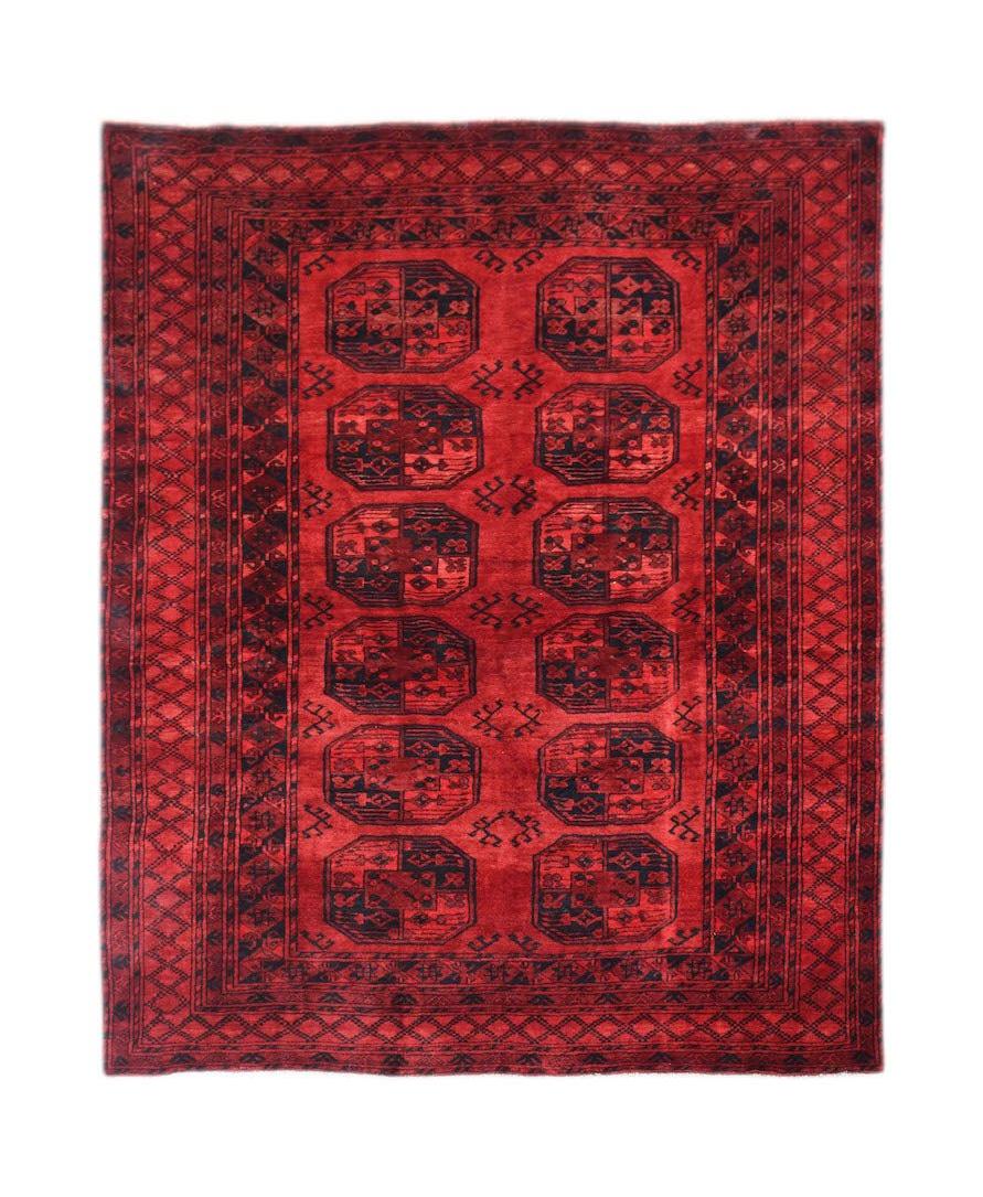 A vintage handmade Afghan Turkmen rug featuring a red field with repeating elephant foot motifs.
