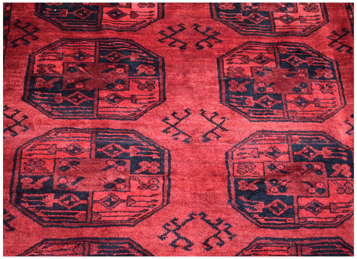 A vintage Afghan Turkmen wool rug featuring a repeating red and black elephant foot motif.
