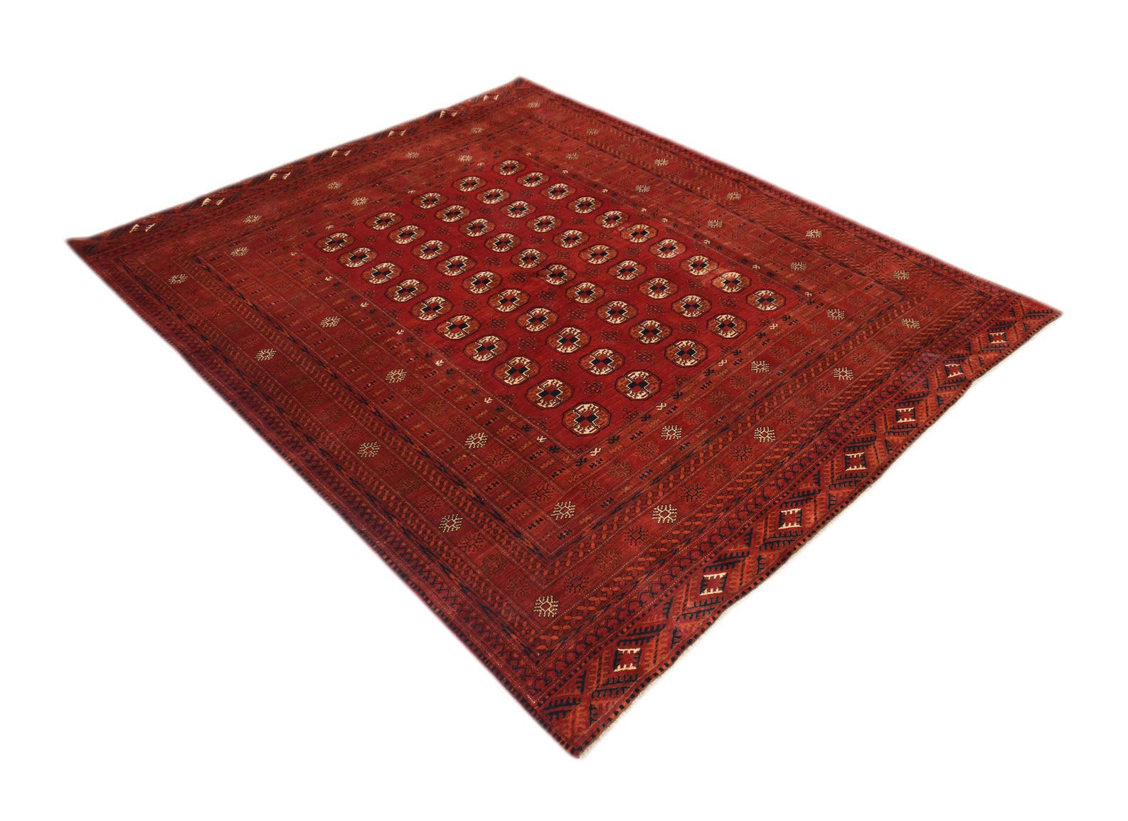A vintage handmade Afghan Turkmen rug featuring a deep red field with repeating elephant foot motifs.