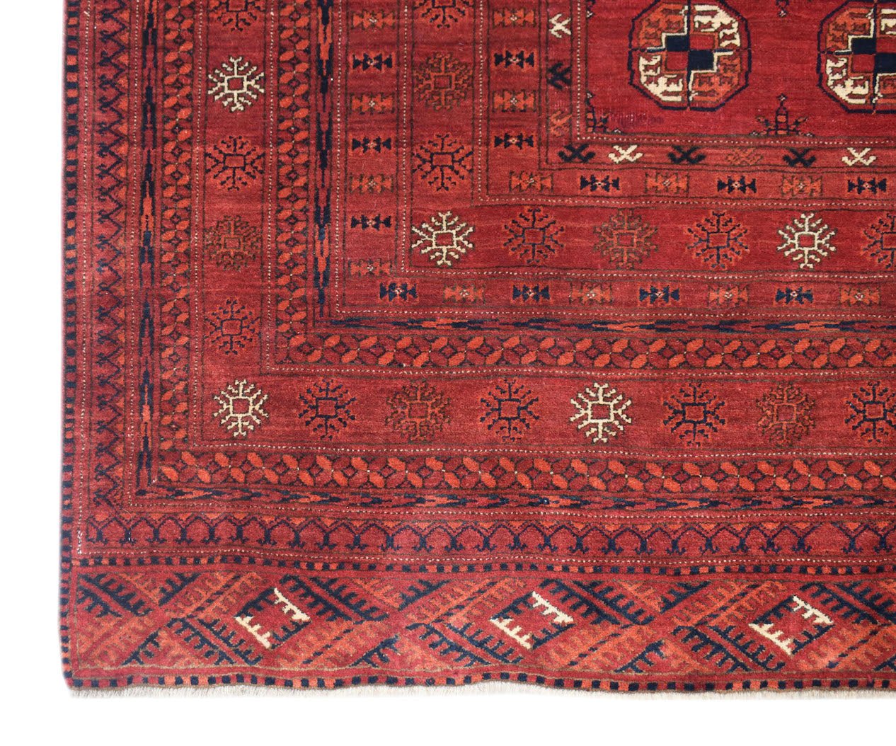 A vintage Afghan Turkmen rug featuring a red field with geometric elephant foot motifs.