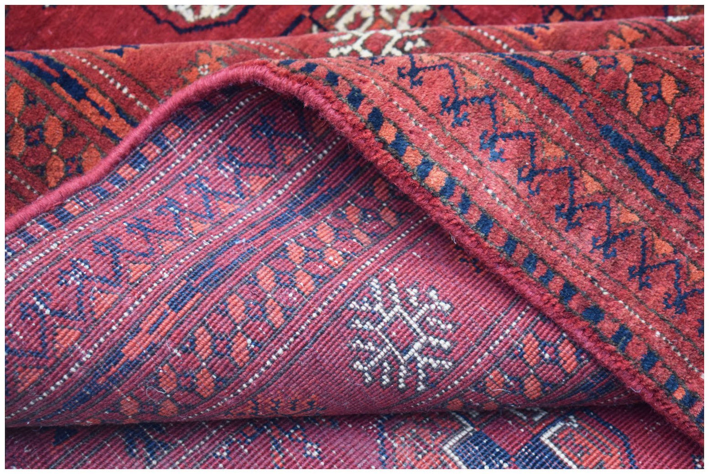 A vintage handmade Afghan Turkmen wool rug featuring a red geometric Elephant's Foot pattern.