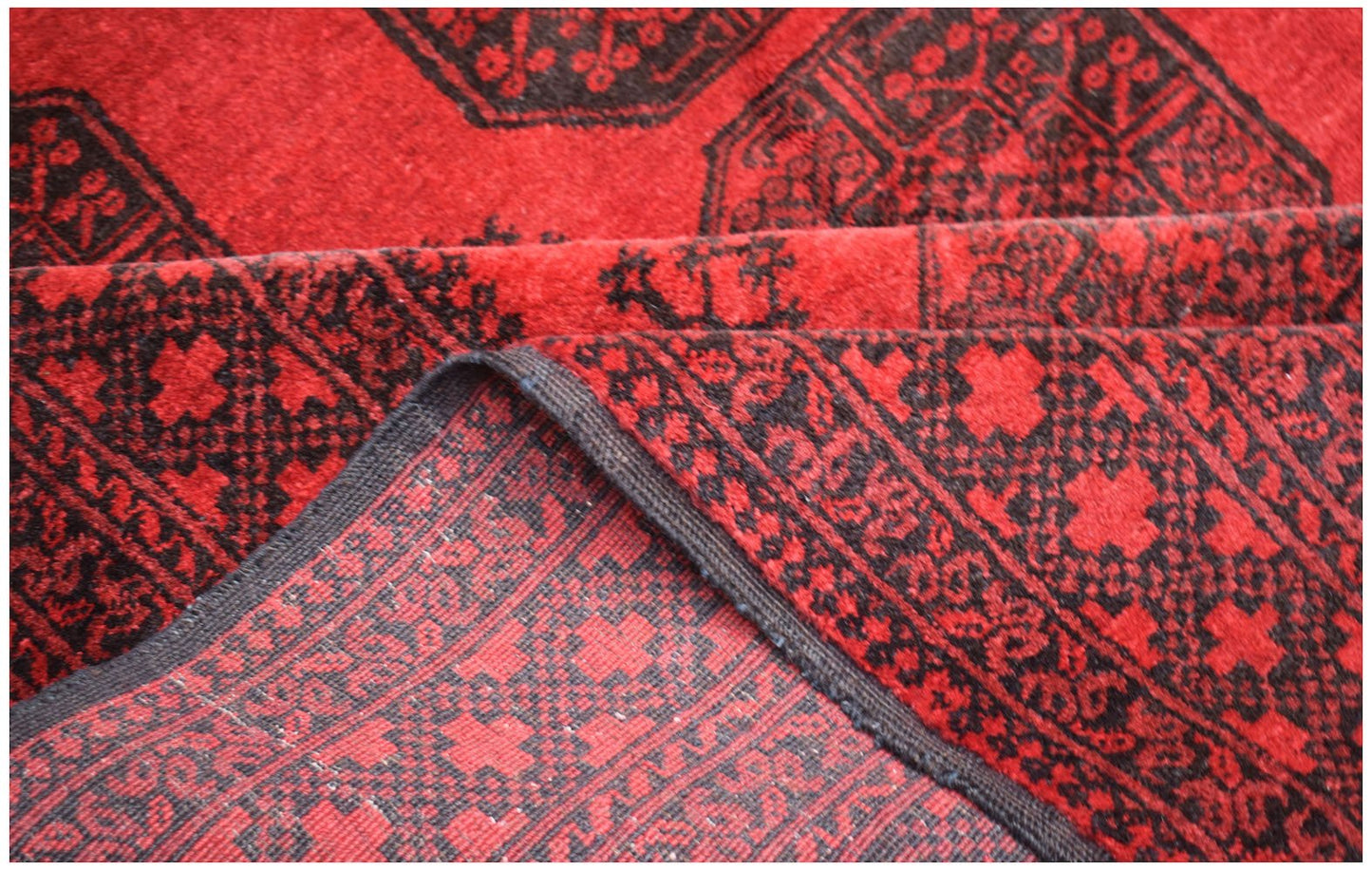 A vintage handmade Afghan Turkmen wool rug featuring a traditional red and black geometric pattern.