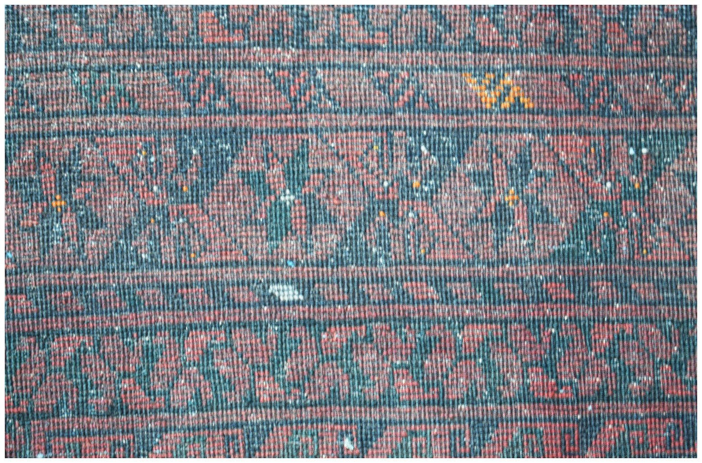 A vintage Afghan Turkmen rug featuring a repeating geometric elephant foot motif in red and black.