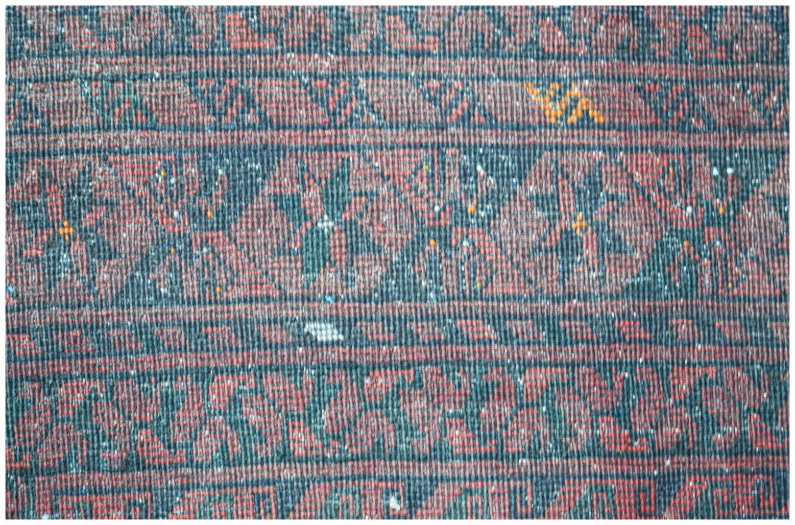 A vintage Afghan Turkmen rug featuring a repeating geometric elephant foot motif in red and black.