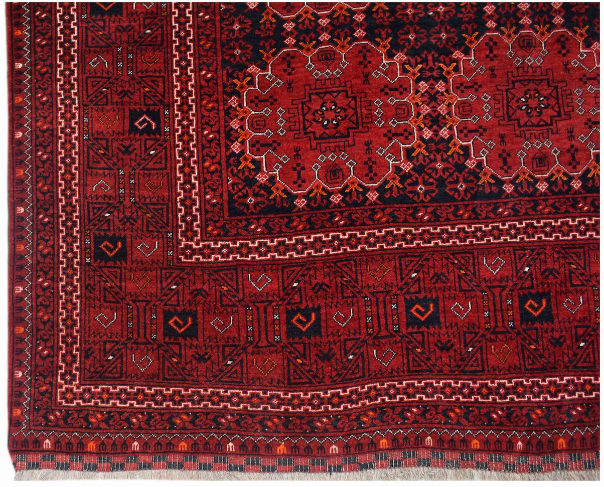 A vintage Afghan Turkmen rug featuring a deep red field with geometric elephant foot motifs.