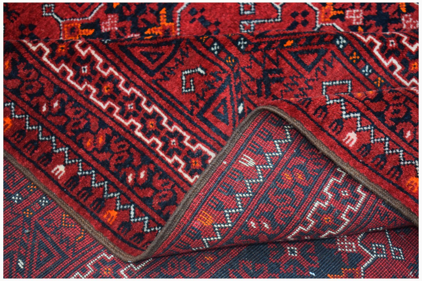 A vintage Afghan Turkmen rug featuring a red field with geometric elephant foot motifs.