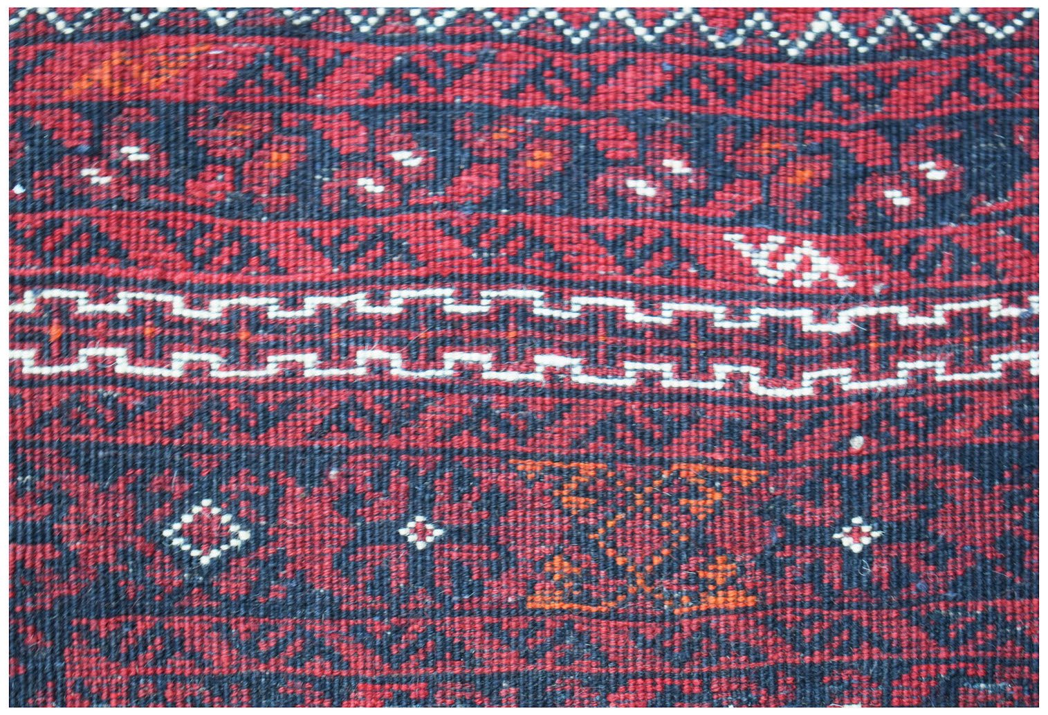 A vintage Afghan Turkmen wool rug featuring traditional geometric patterns in red and black.