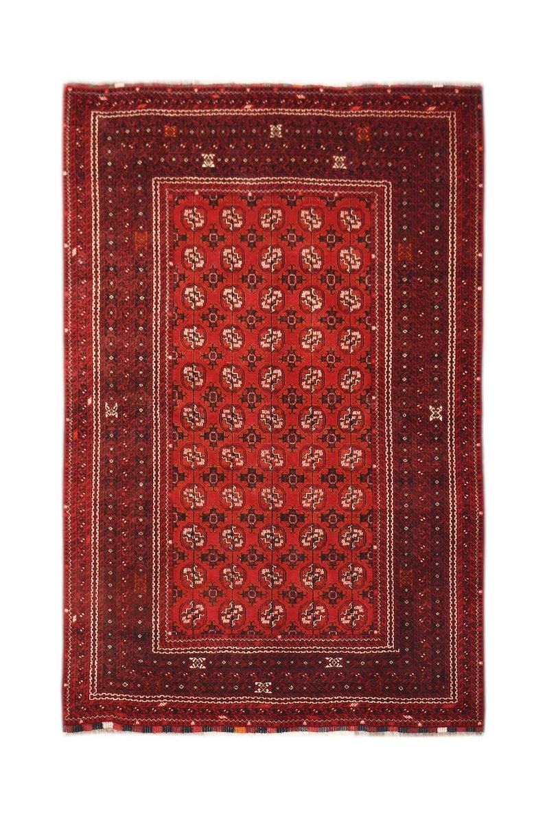 A vintage handmade Afghan Turkmen rug featuring a repeating red elephant foot motif.
