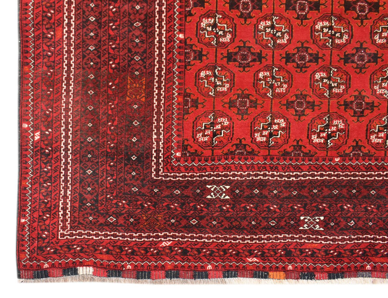 A vintage handmade Afghan Turkmen rug featuring a red field with repeating geometric elephant foot motifs.