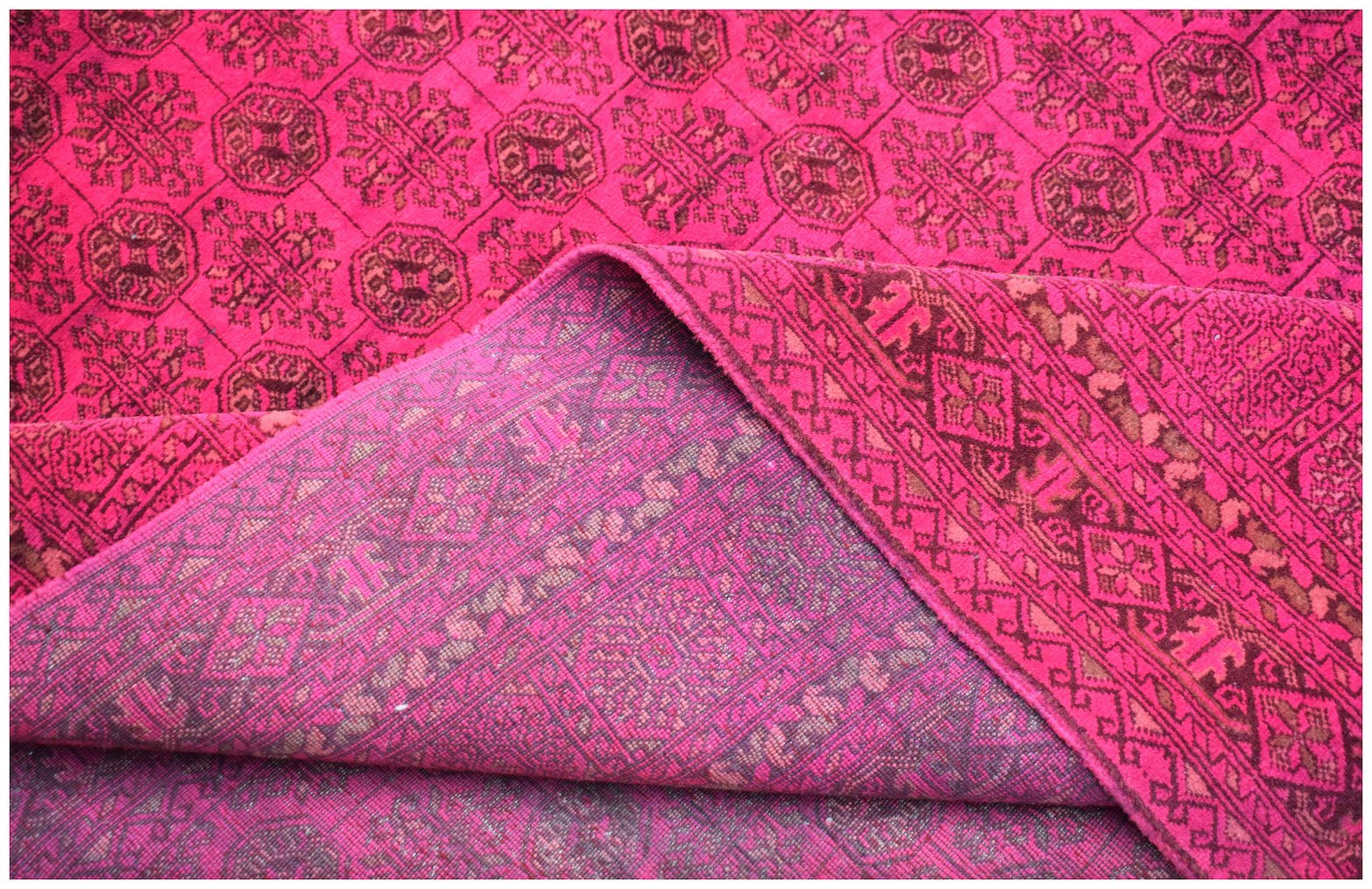 A vintage Afghan Turkmen rug featuring a vibrant pink field with repeating geometric motifs.