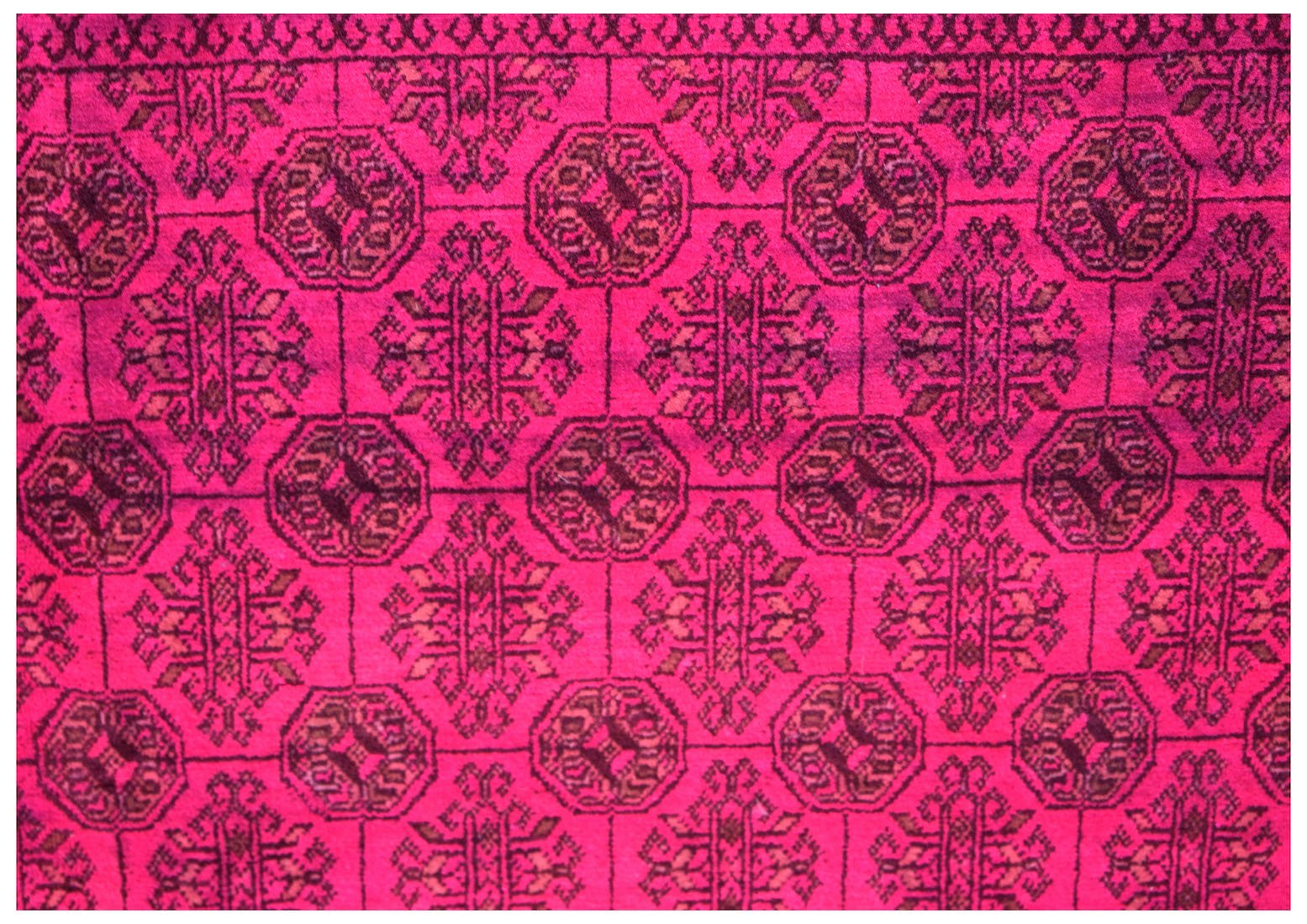 A vintage Afghan Turkmen rug featuring a repeating geometric elephant foot motif in deep pink.