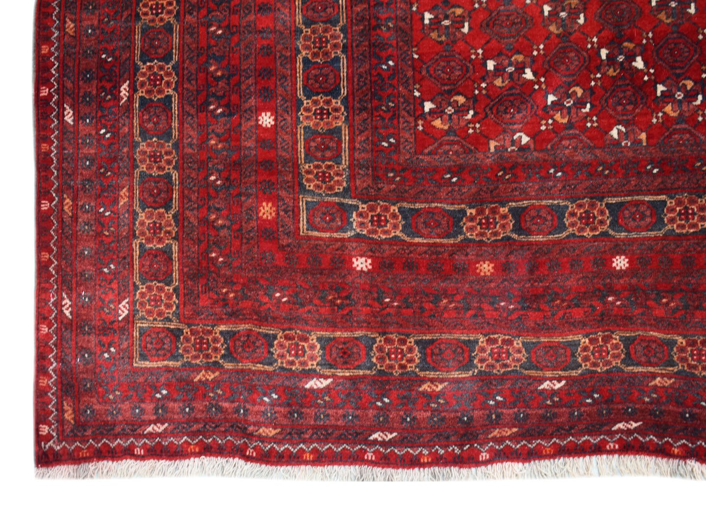 A vintage Afghan Turkmen rug featuring a deep red field with geometric elephant foot motifs.