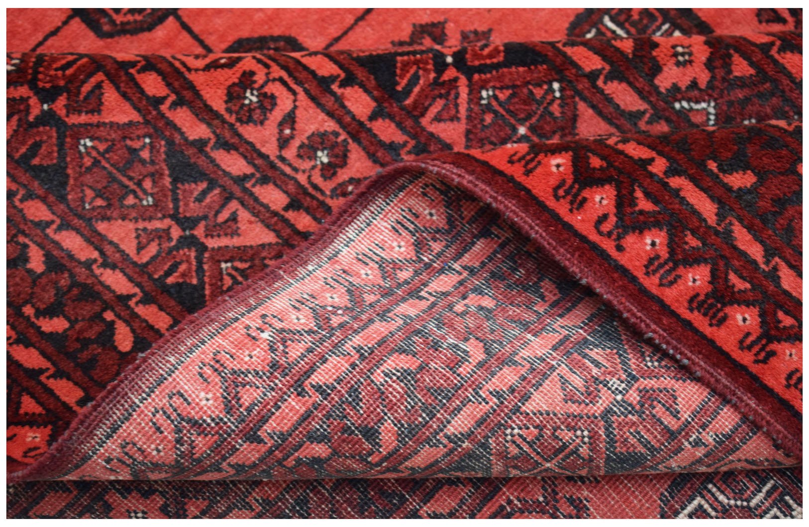 A vintage handmade Afghan Turkmen rug featuring a red geometric Elephant's Foot motif.