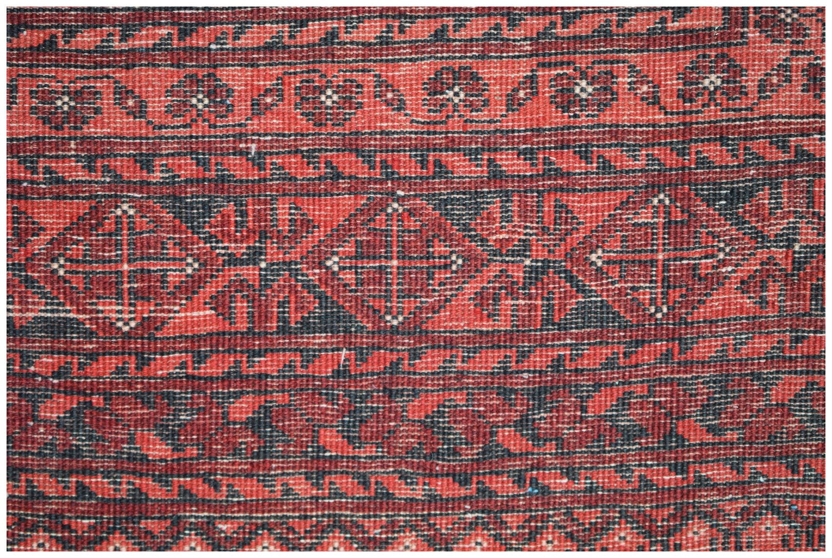 A vintage Afghan Turkmen rug featuring a geometric elephant foot motif in red and black wool.
