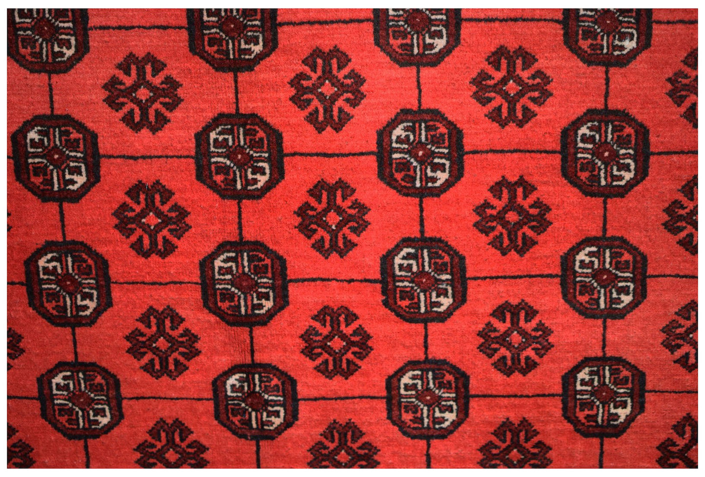 A vintage Afghan Turkmen rug featuring a repeating red geometric elephant foot motif.
