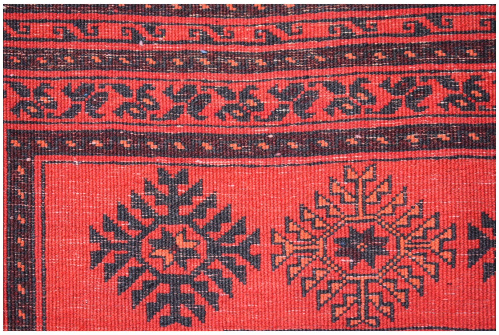 A vintage handmade Afghan Turkmen wool rug featuring traditional red and black geometric motifs.