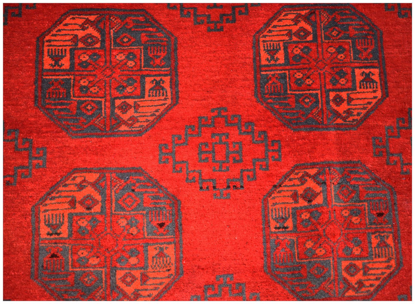 A vintage Afghan Turkmen rug featuring a repeating red and black geometric elephant foot motif.