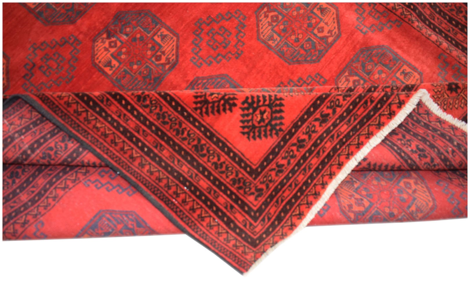 A vintage Afghan Turkmen rug featuring a red field with repeating geometric elephant foot motifs.