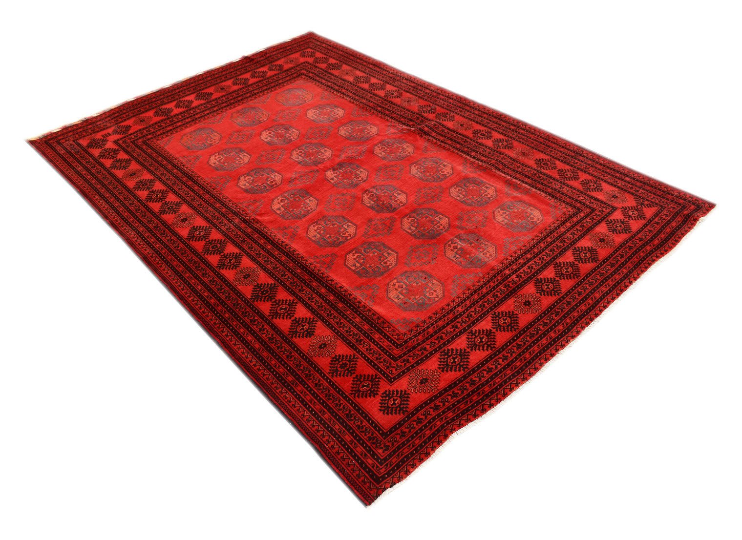A vintage handmade Afghan Turkmen rug featuring a red field with repeating geometric elephant foot motifs.