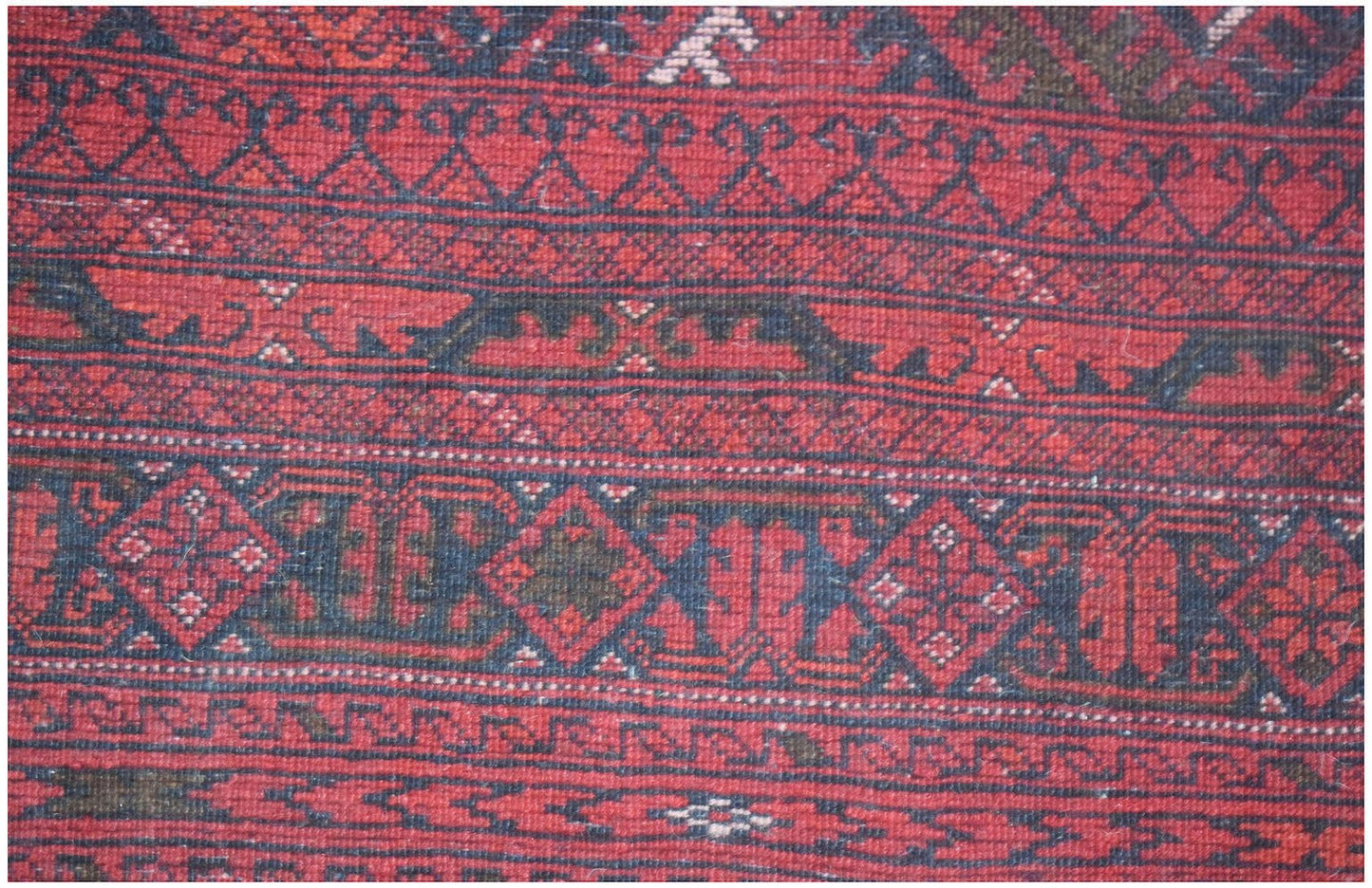 A vintage handmade Afghan Turkmen rug featuring traditional red and dark blue geometric patterns.